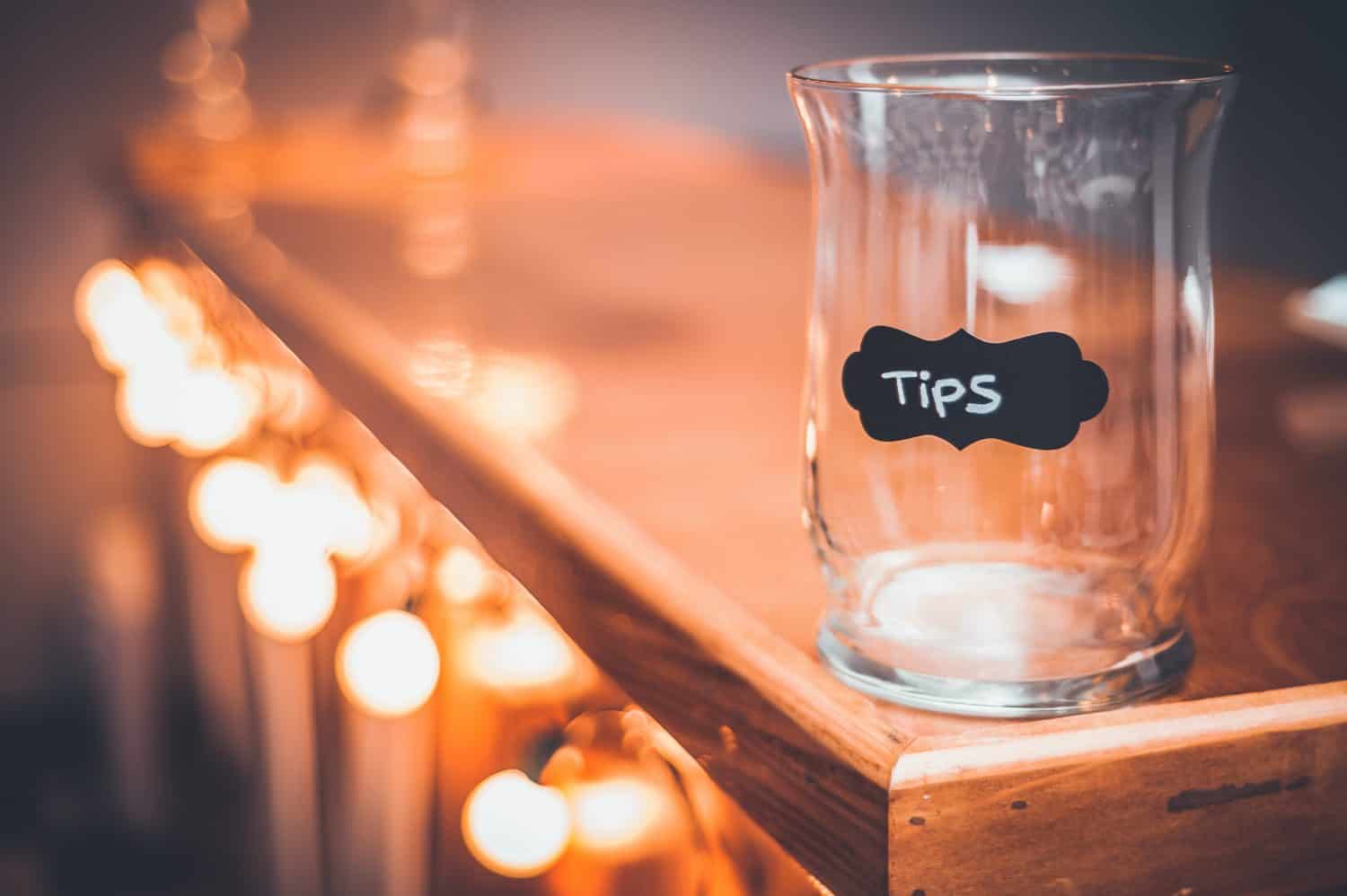 Tips Jar on a bar countertop. Bokeh lights along a bar counter with a tip Jar at the end. Gold Bokeh lights.