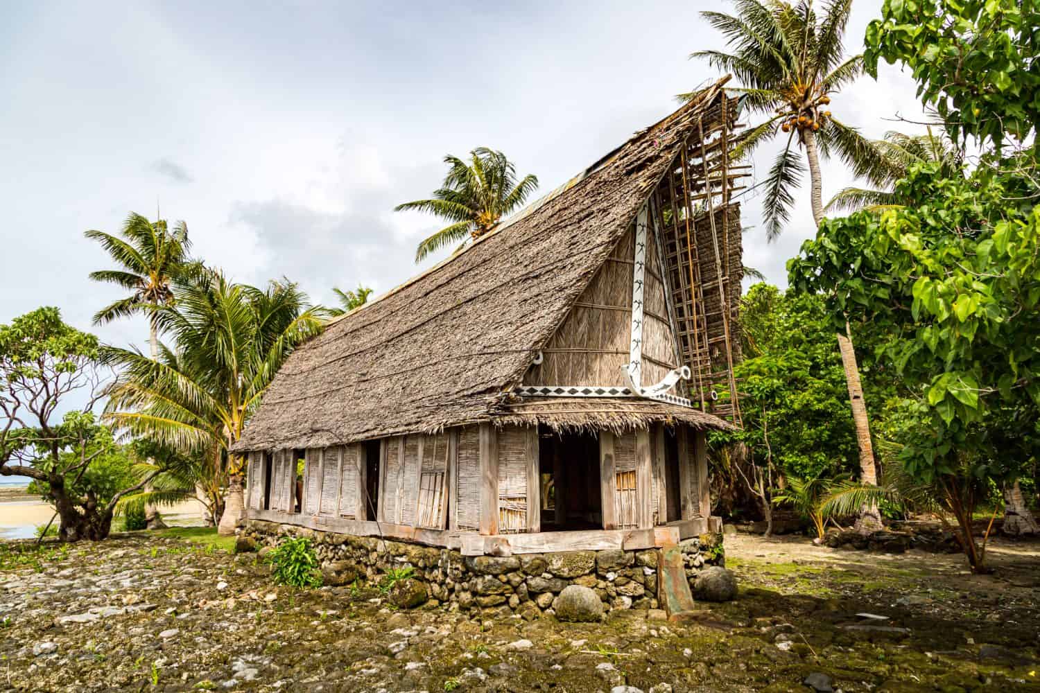 Old traditional thatched yapese men&#039;s meeting house faluw (fale), on an elevated limestone platform foundation. Shore of South Pacific ocean. Yap island, Federated States of Micronesia, Oceania.