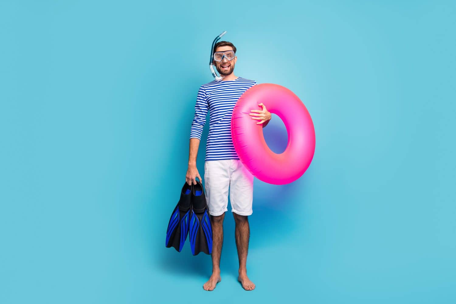 Full body photo of funny excited guy tourist swimmer hold underwater mask breathing tube flippers pink lifebuoy wear striped sailor shirt shorts isolated blue color background