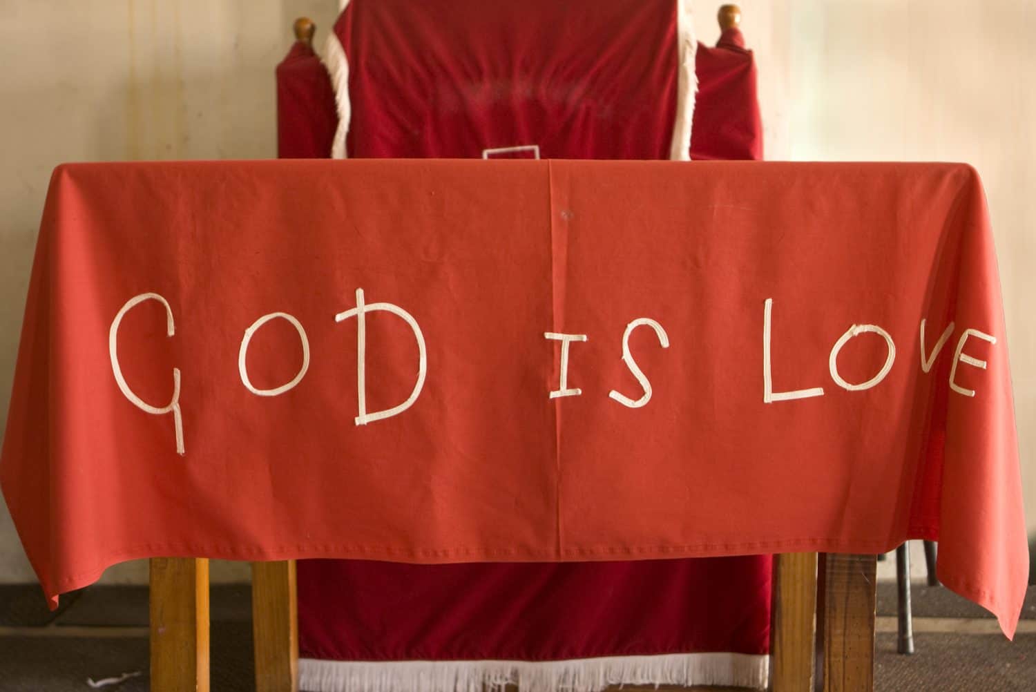 A handmade cloth saying God Is Love. This covers the altar of a make-shift church in the township of Kayamandi, South Africa.