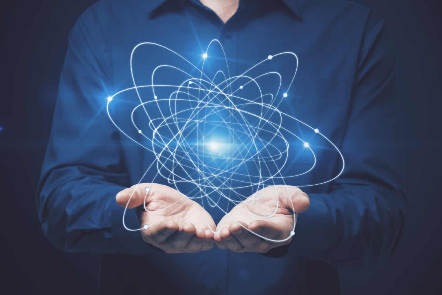 Businessman holding atom on dark background. Science concept