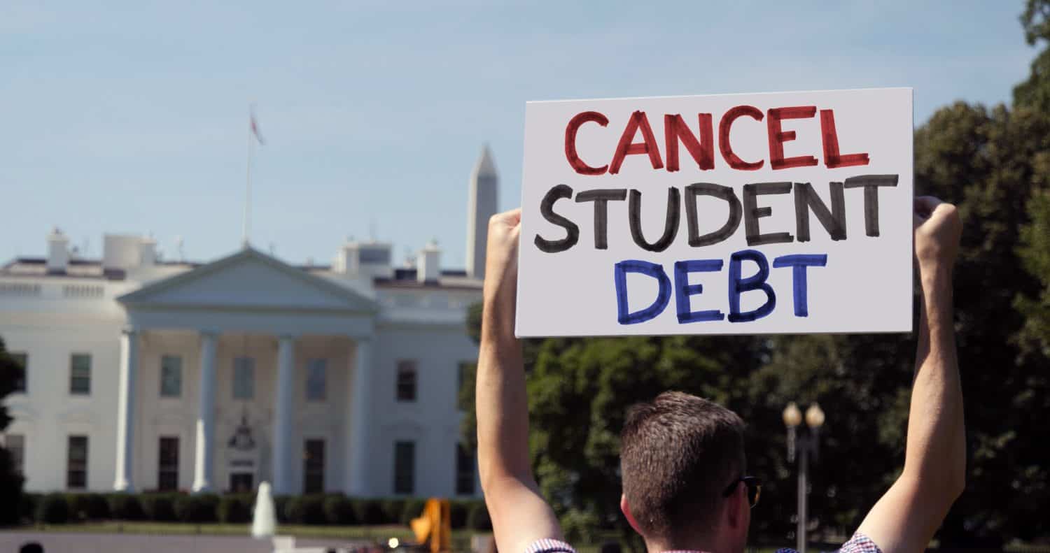 A man holds an CANCEL STUDENT DEBT protest sign in front of the White House on a sunny summer day. Student debt was a hot topic during the COVID-19 pandemic.