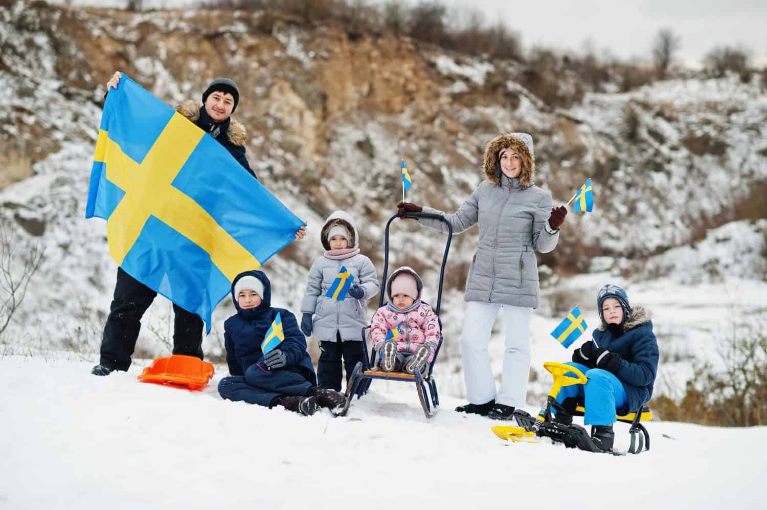 Scandinavian family with Sweden flag in winter swedish landscape.