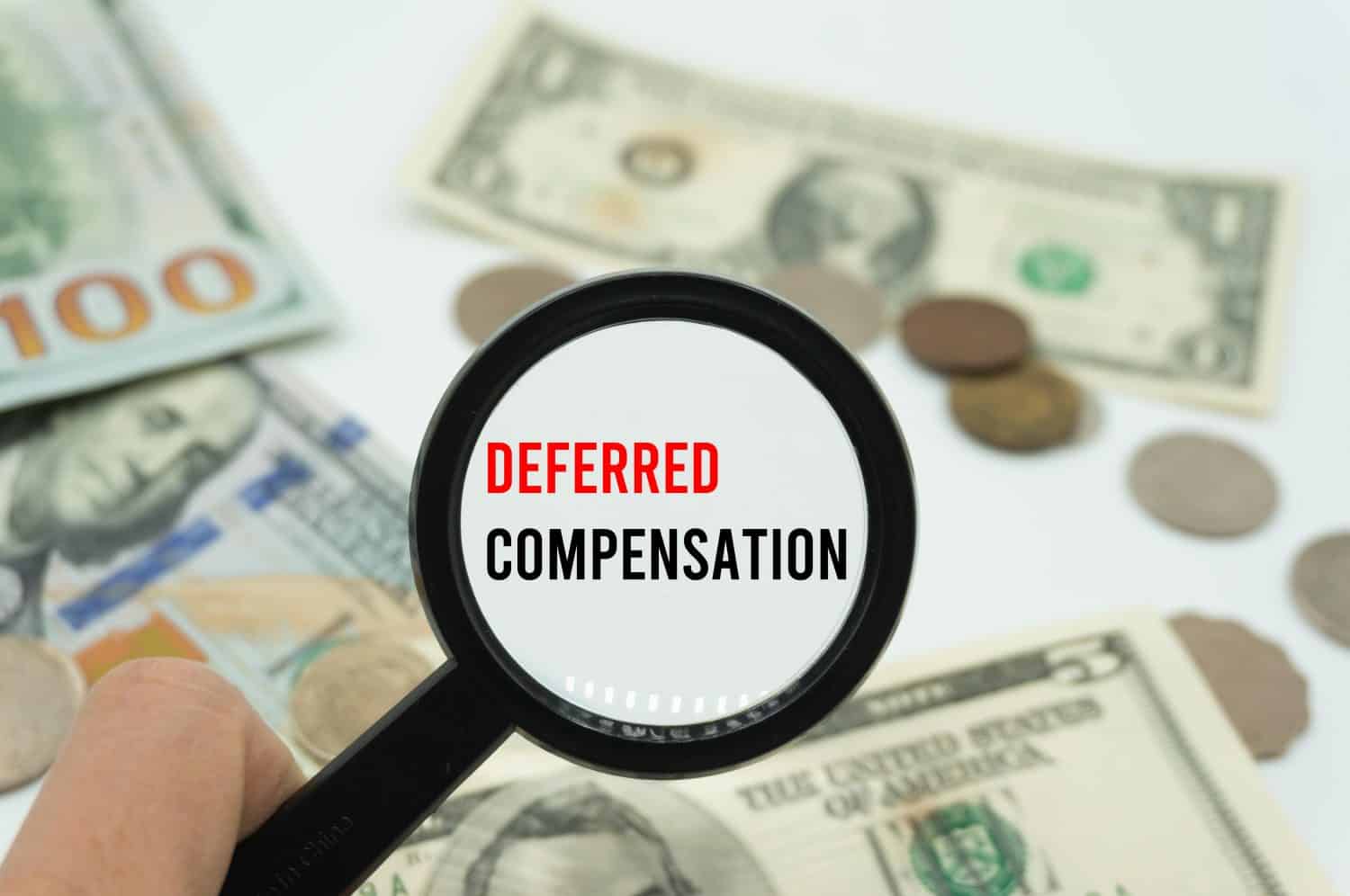 Deferred Compensation.Magnifying glass showing the words.Background of banknotes and coins.basic concepts of finance.Business theme.Financial terms.