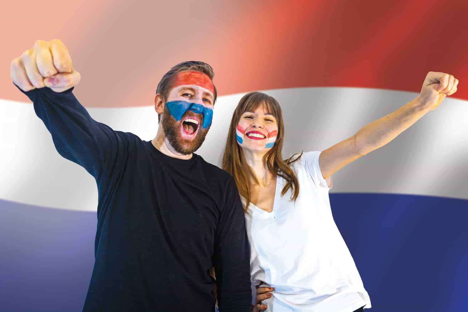 fans of the netherlands football team celebrate winning a match during the world championships; happy netherlands soccer fans with painted faces and the dutch flag in the background
