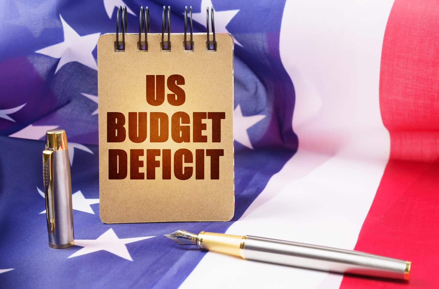 Business concept. Against the background of the American flag is a notepad with the inscription - US budget deficit