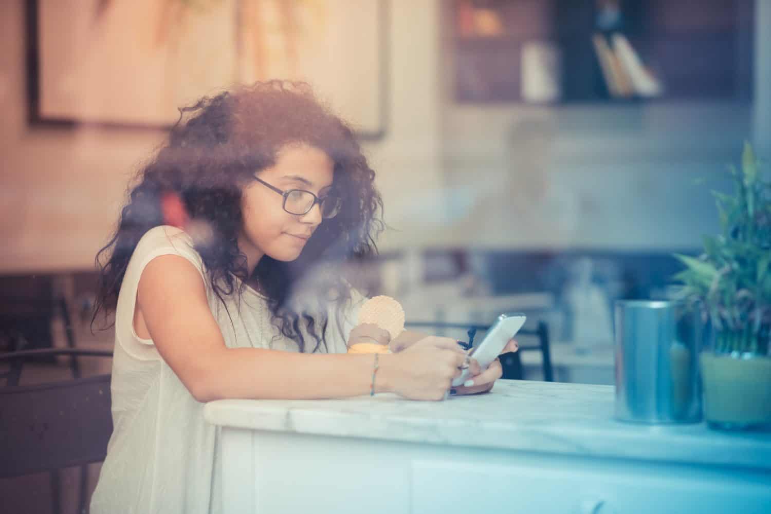 young beautiful moroccan curly woman using smartphone at the bar