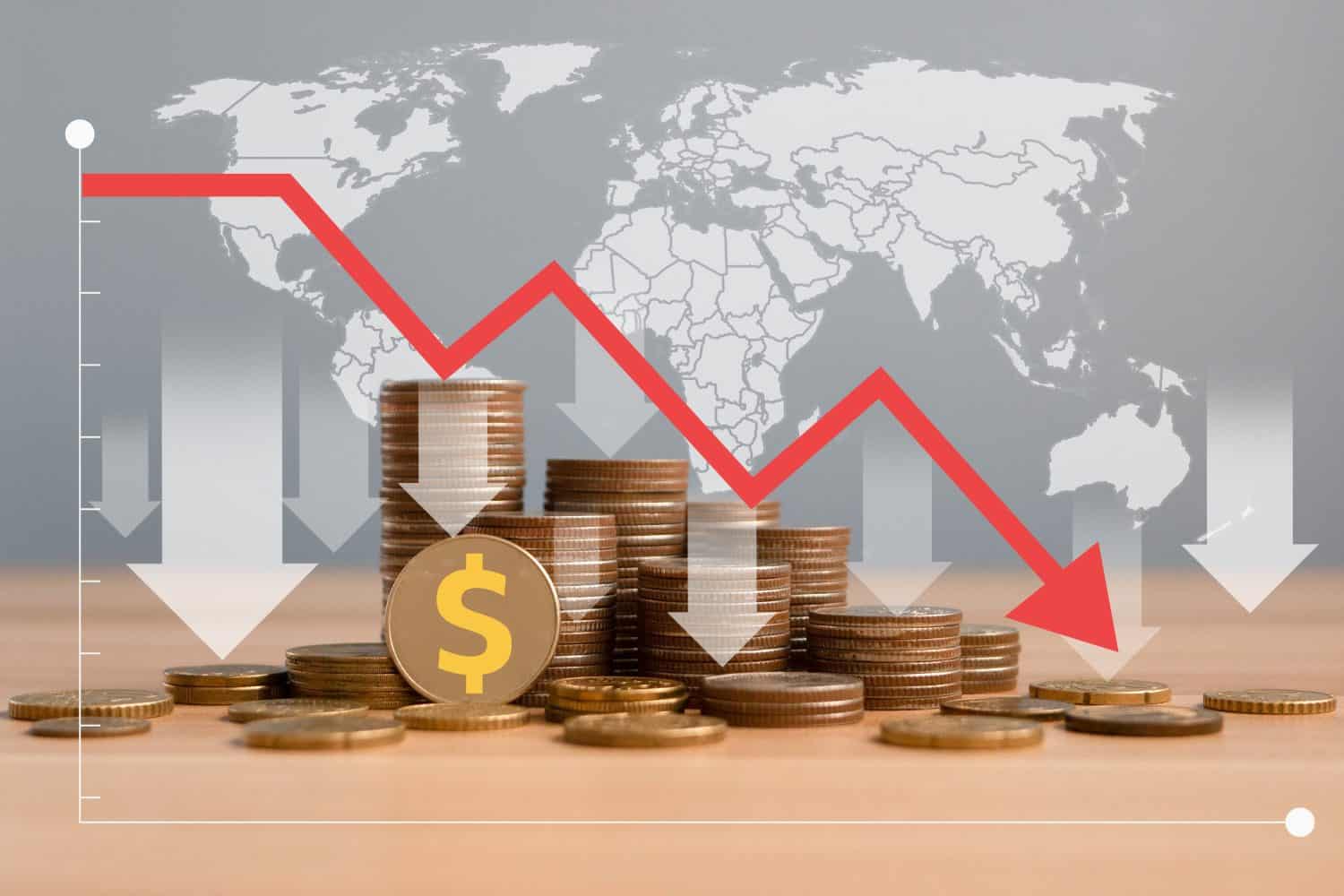 Economic crisis, Inflation. The recession of the economy. Stacks of coins with down arrow and world map.