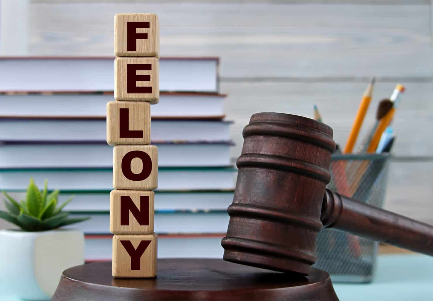 The word FELONY on wooden cubes against the background of the judge&#039;s gavel and stand. Business concept