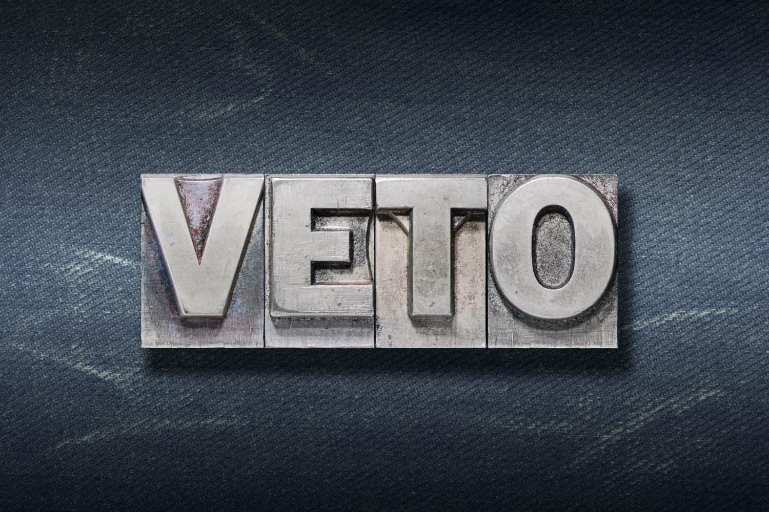 veto (I forbid) word made from metallic letterpress on dark jeans background