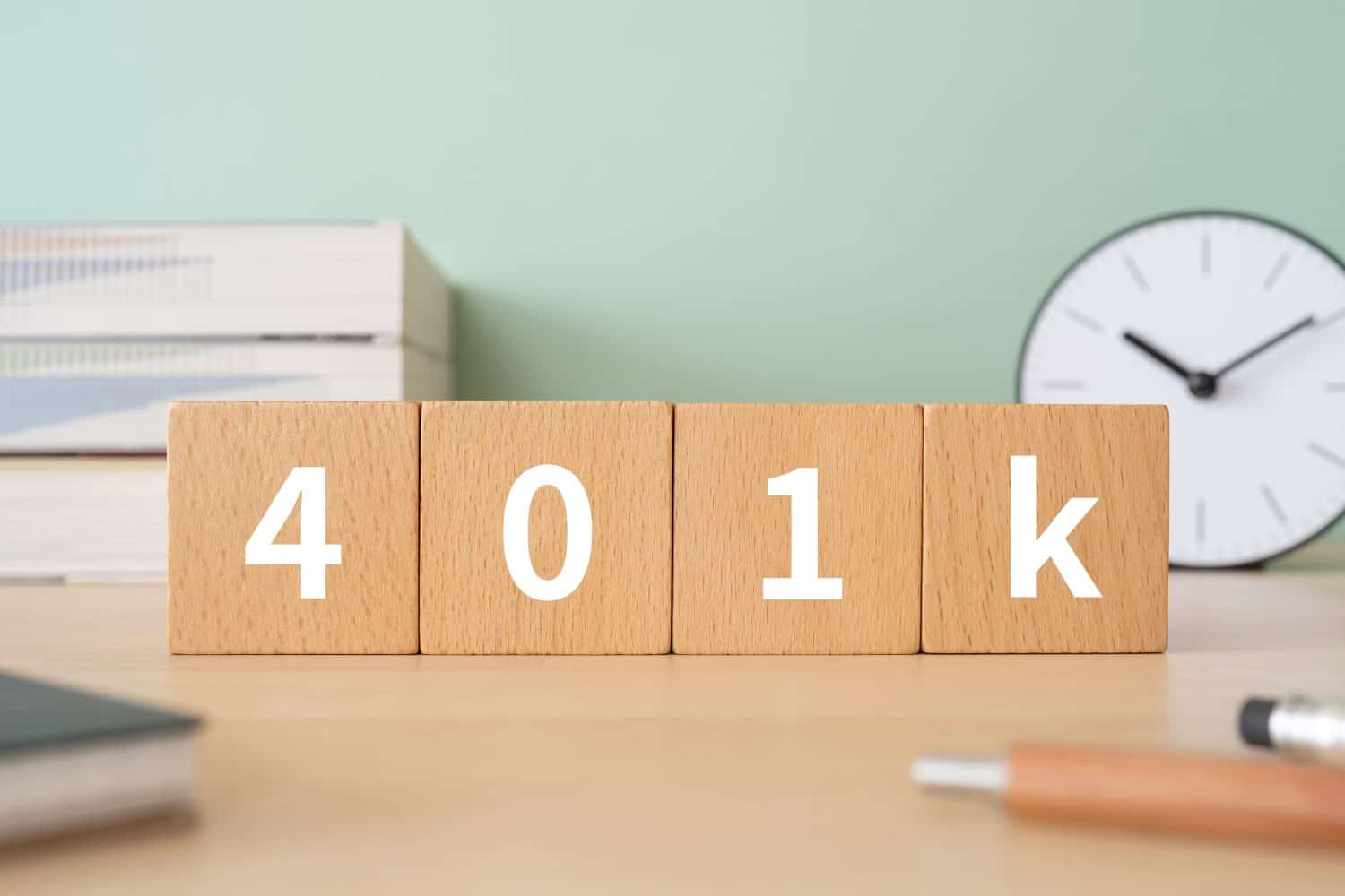 Wooden blocks with "401k" text of concept, pens, notebooks, and books.