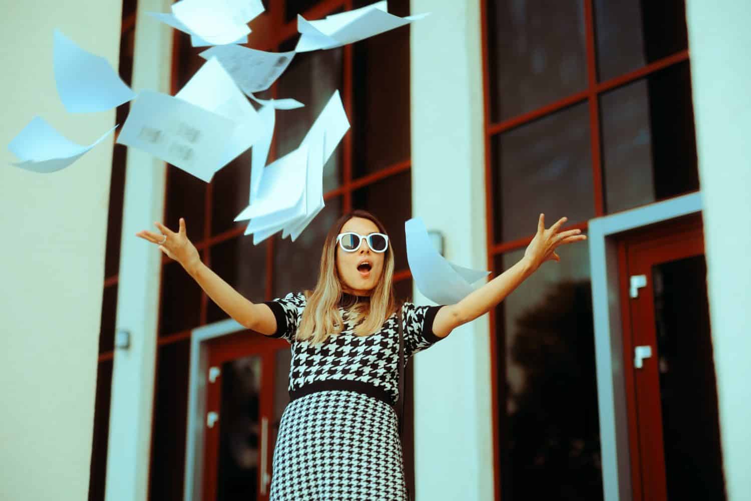 Carefree Businesswoman Throwing Documents outside Office Building. Office worker quitting job and going on vacation