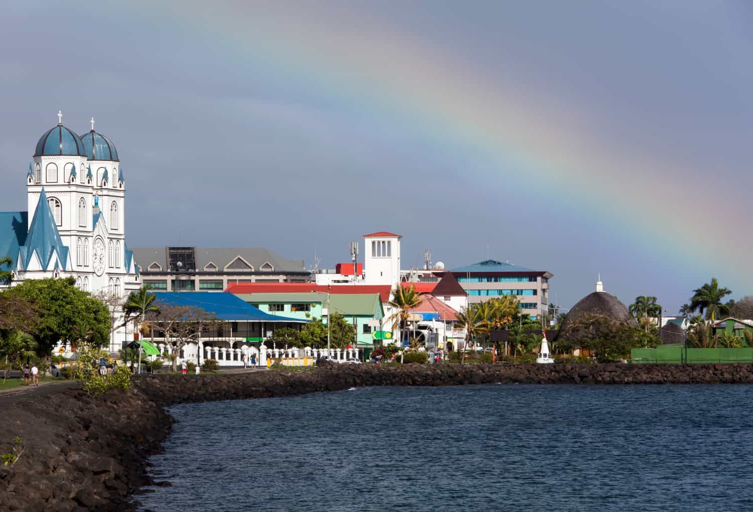 The morning view of a cloudy sky with a rainbow over Apia downtown and cathedral (Samoa).