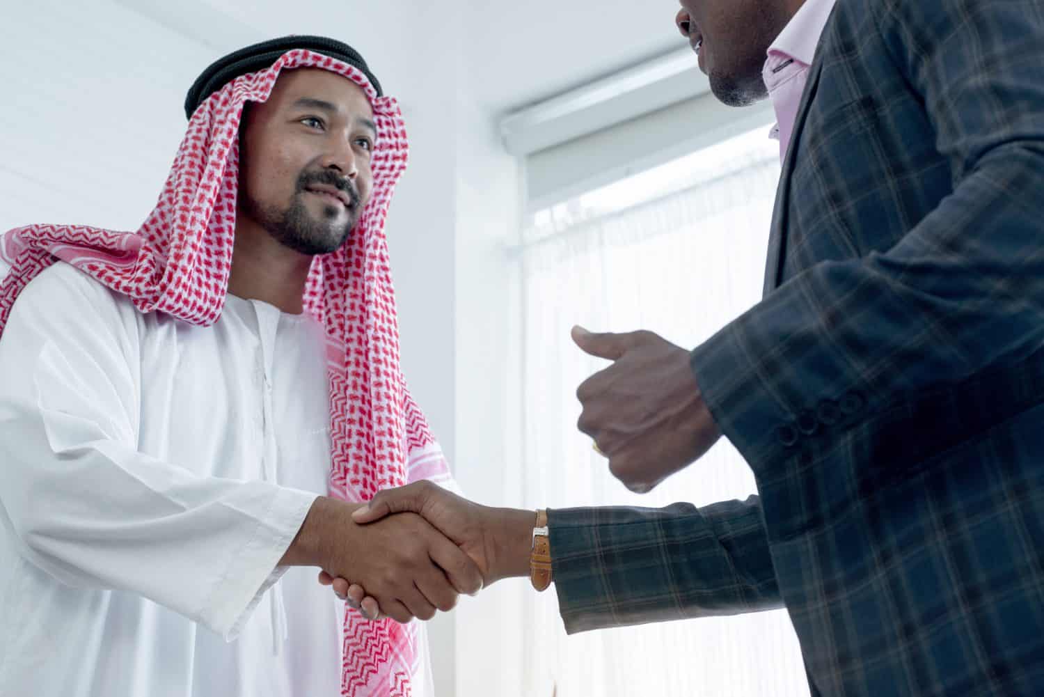 Arab and African businessmen shake hands after a successful business deal in the office, Successfully formed a partnership to open a branch company overseas