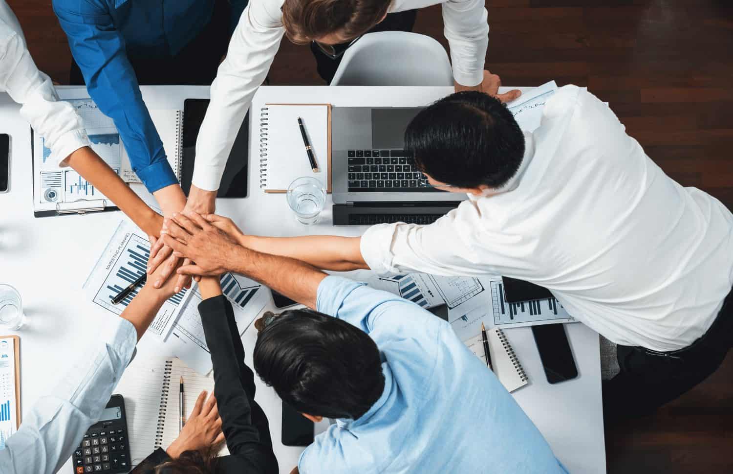 Top view diverse office worker join hand together in office room symbolize business synergy and strong productive teamwork in workplace. Cooperation and unity between business employee. Prudent