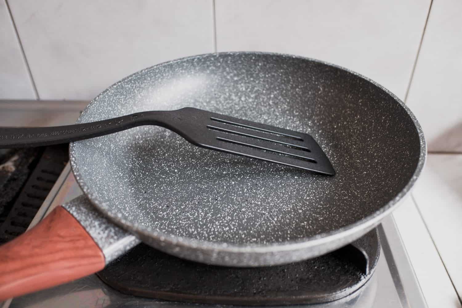 A non-stick Teflon frying pan with a plastic spatula on the stove, cooking utensil, in the kitchen.