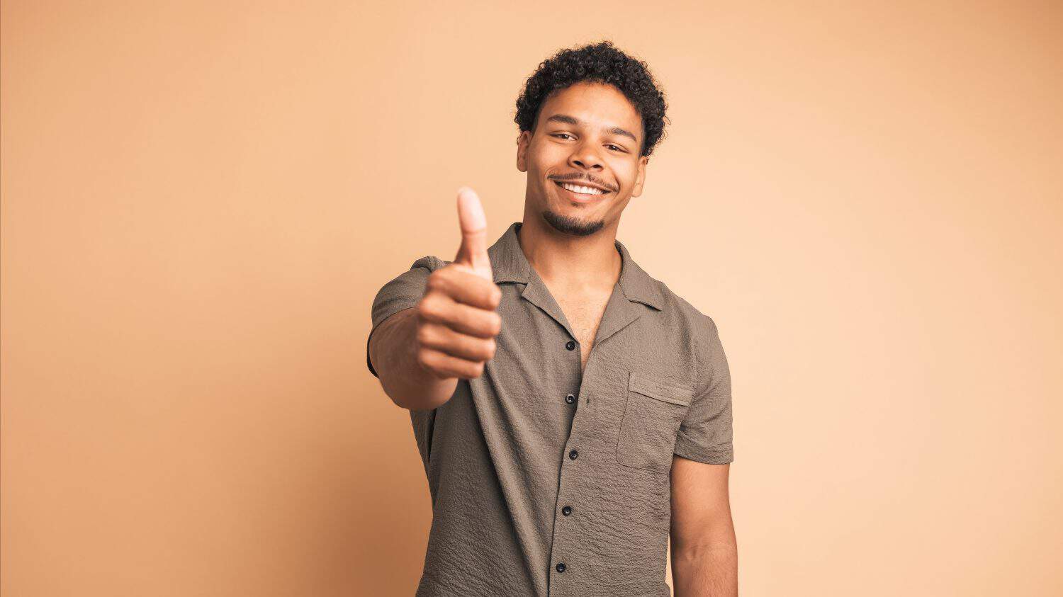 Smiling man making thumbs up gesture and nodding to show approval