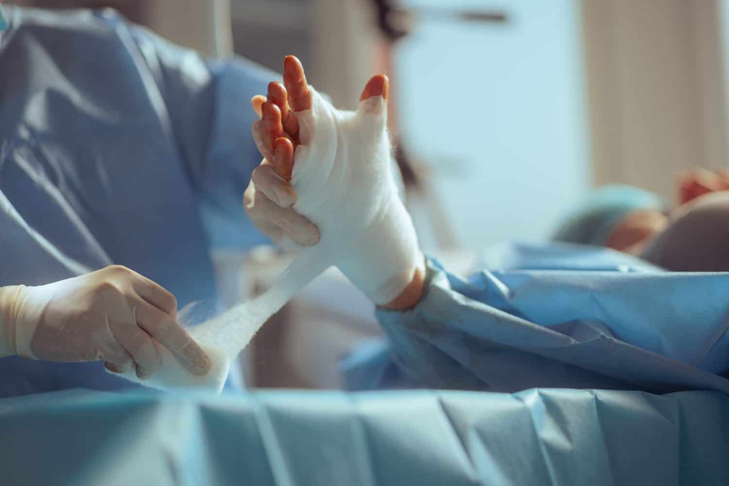 Orthopedist Bandaging a Patient after hand Surgery. Surgeon giving post operator assistance to patient