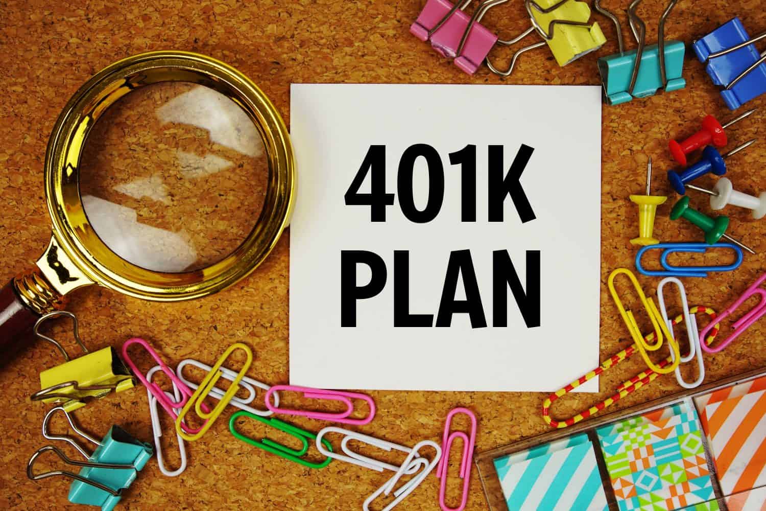 401K Plan text on paper card with magnifying glass and stationery on cork board background