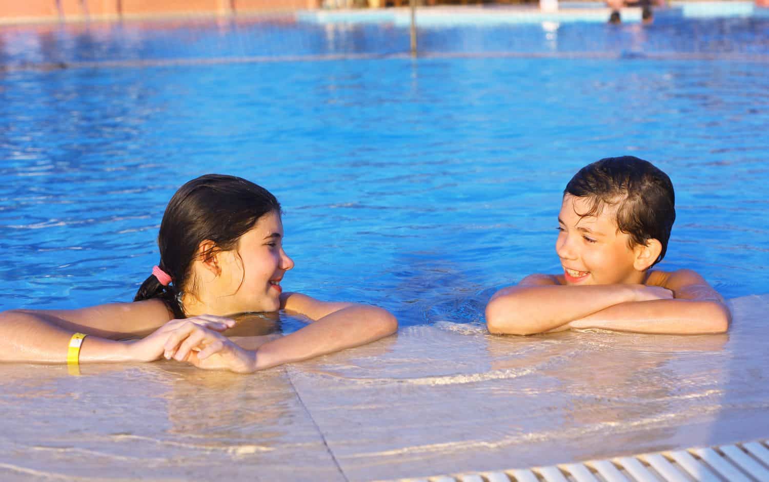 siblings boy and girl play in open air swimming pool at the egyptian sea resort hotel