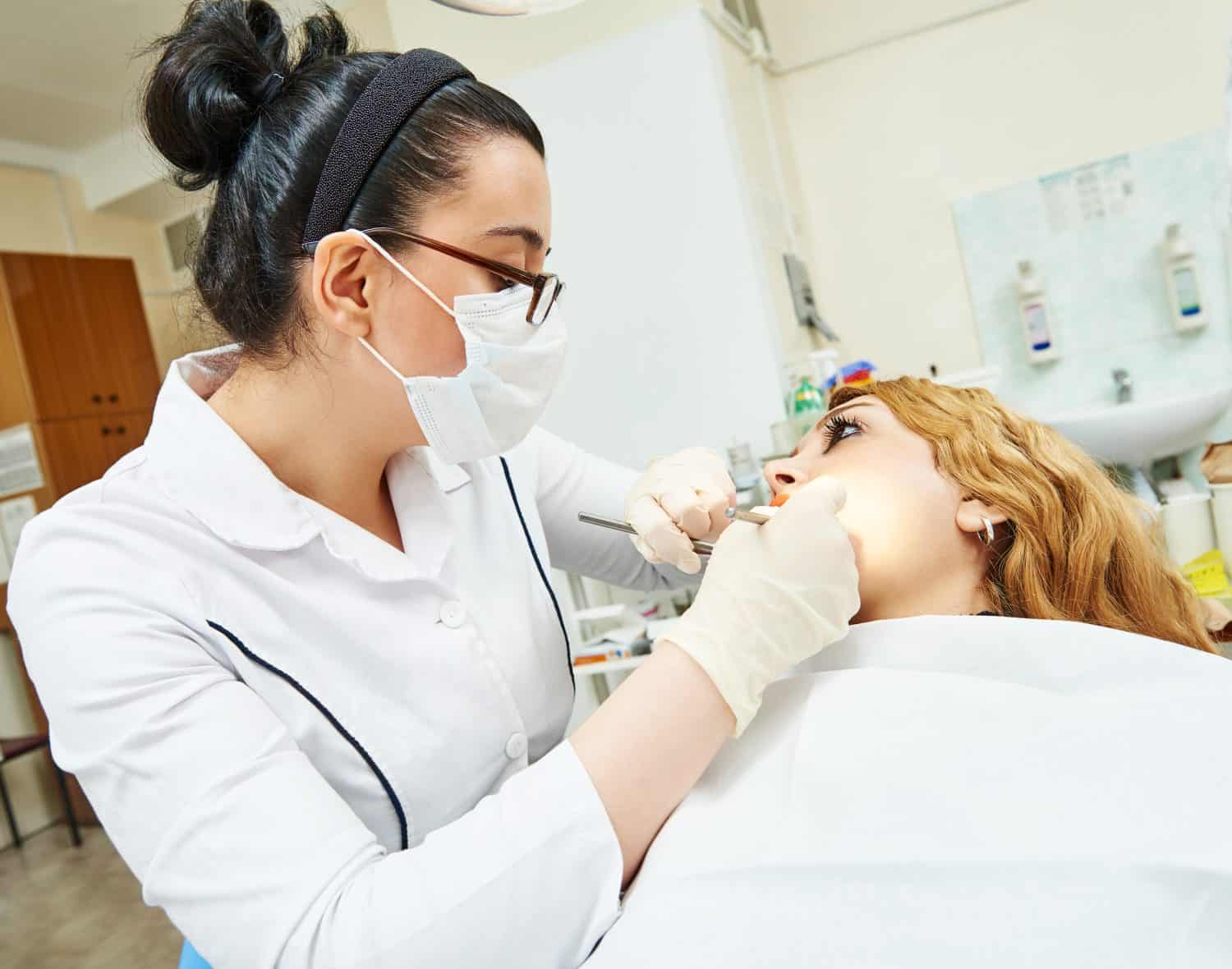 female dentist doctor during tooth examination and treatment