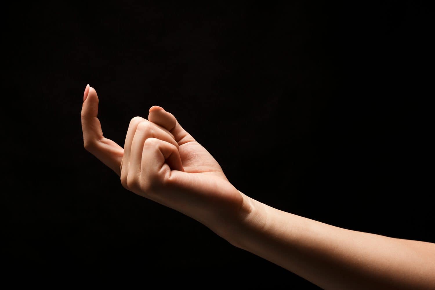 Female hand beckoning with forefinger, isolated on black background. Woman gesturing with one finger, calling up, come here symbol