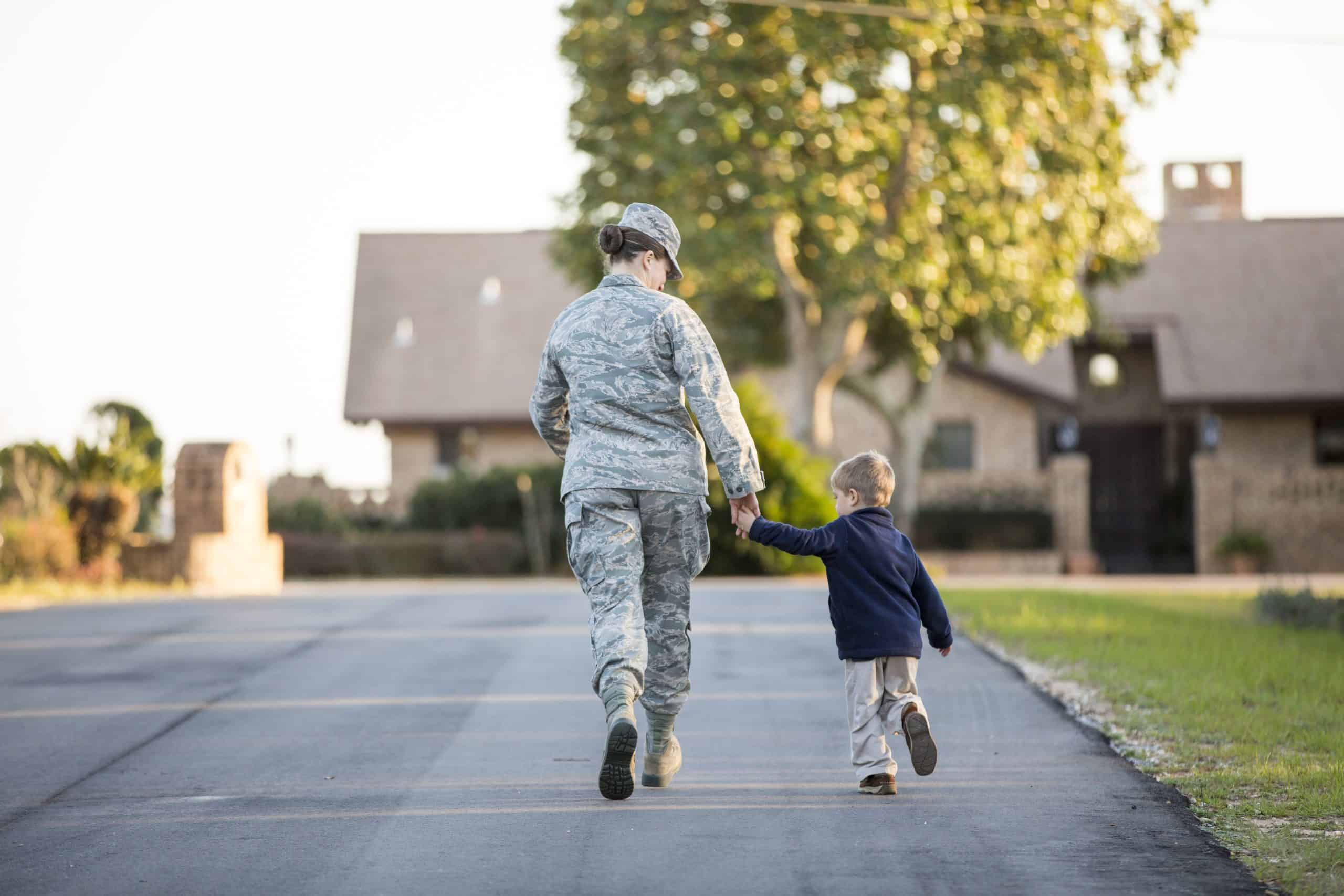 Rear view of female soldier walking with son at military air force base