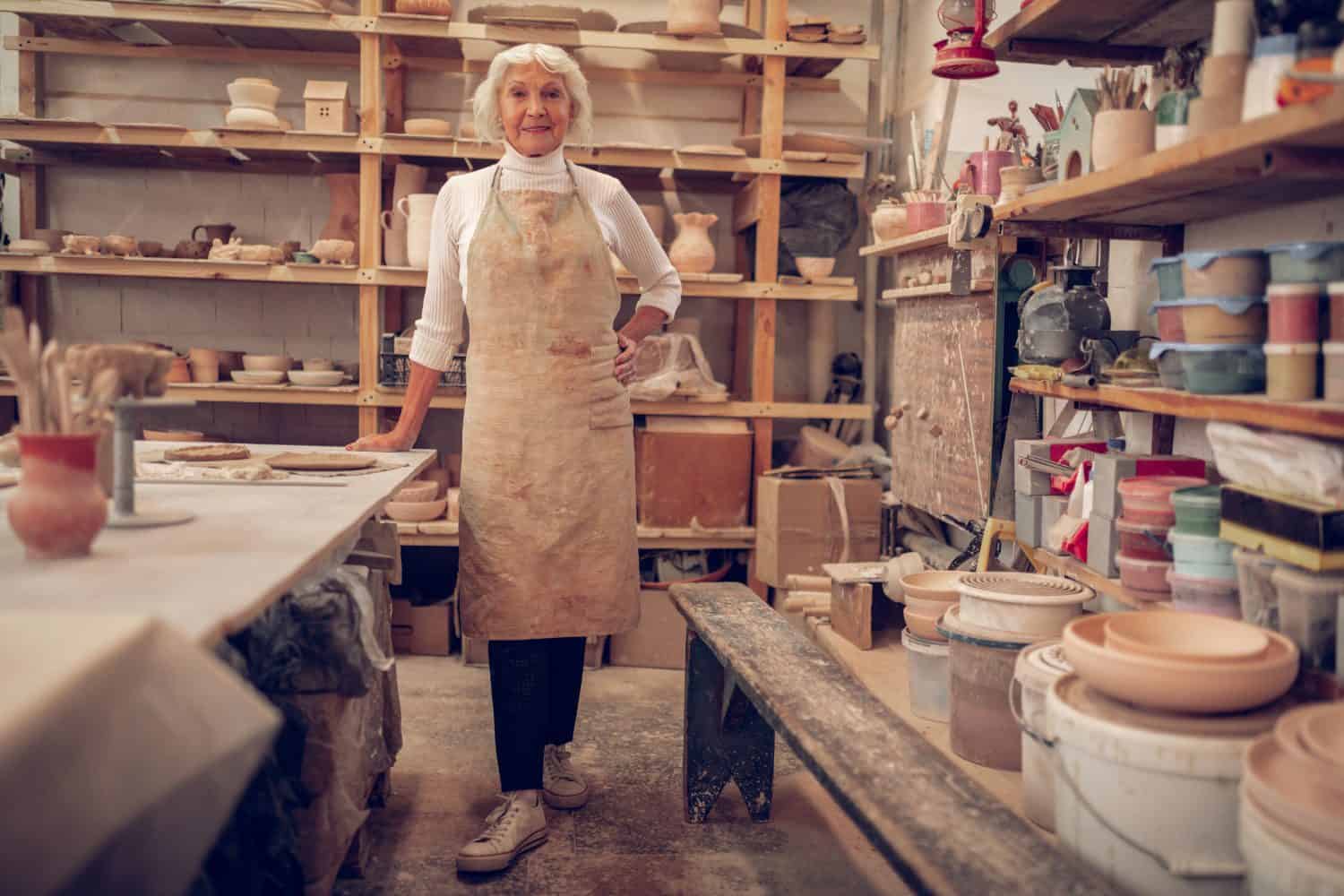 Business owner. Nice senior woman smiling while working in her workshop