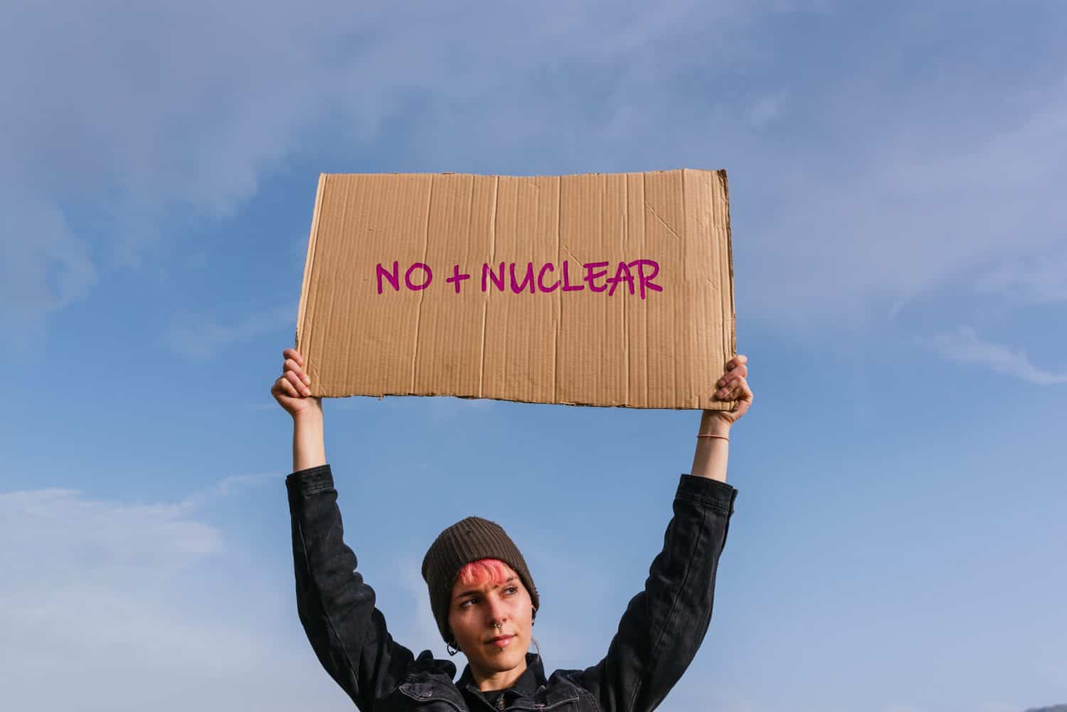 Young activist woman holding a poster against nuclear power and sewage dumping. there is no planet B.