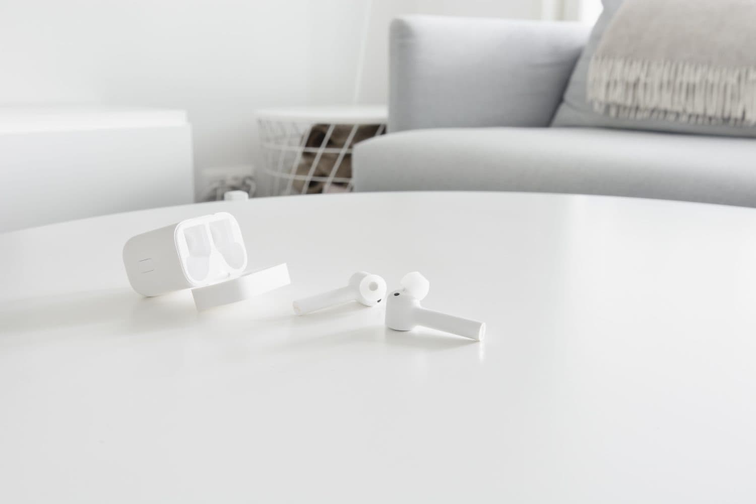 White wireless earbuds with charging case on a wooden table.