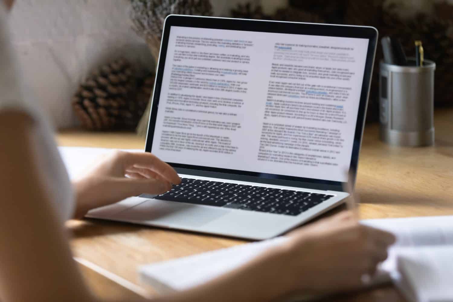 Close up view of modern technology digital gadget opened computer with electronic documents on screen. Young woman preparing report or reading scientific article, studying at home, education concept.