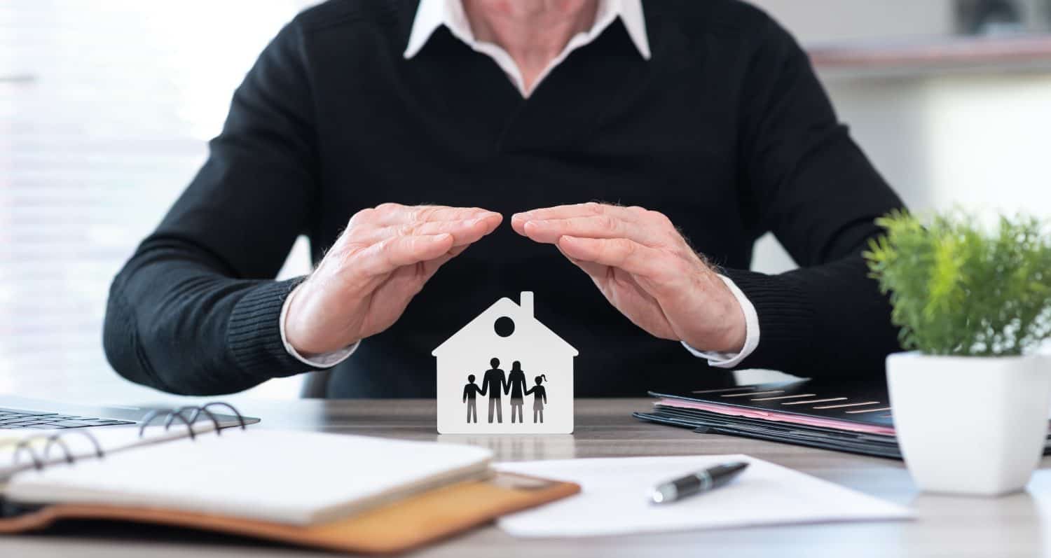 Insurer protecting a family and a house with his hands