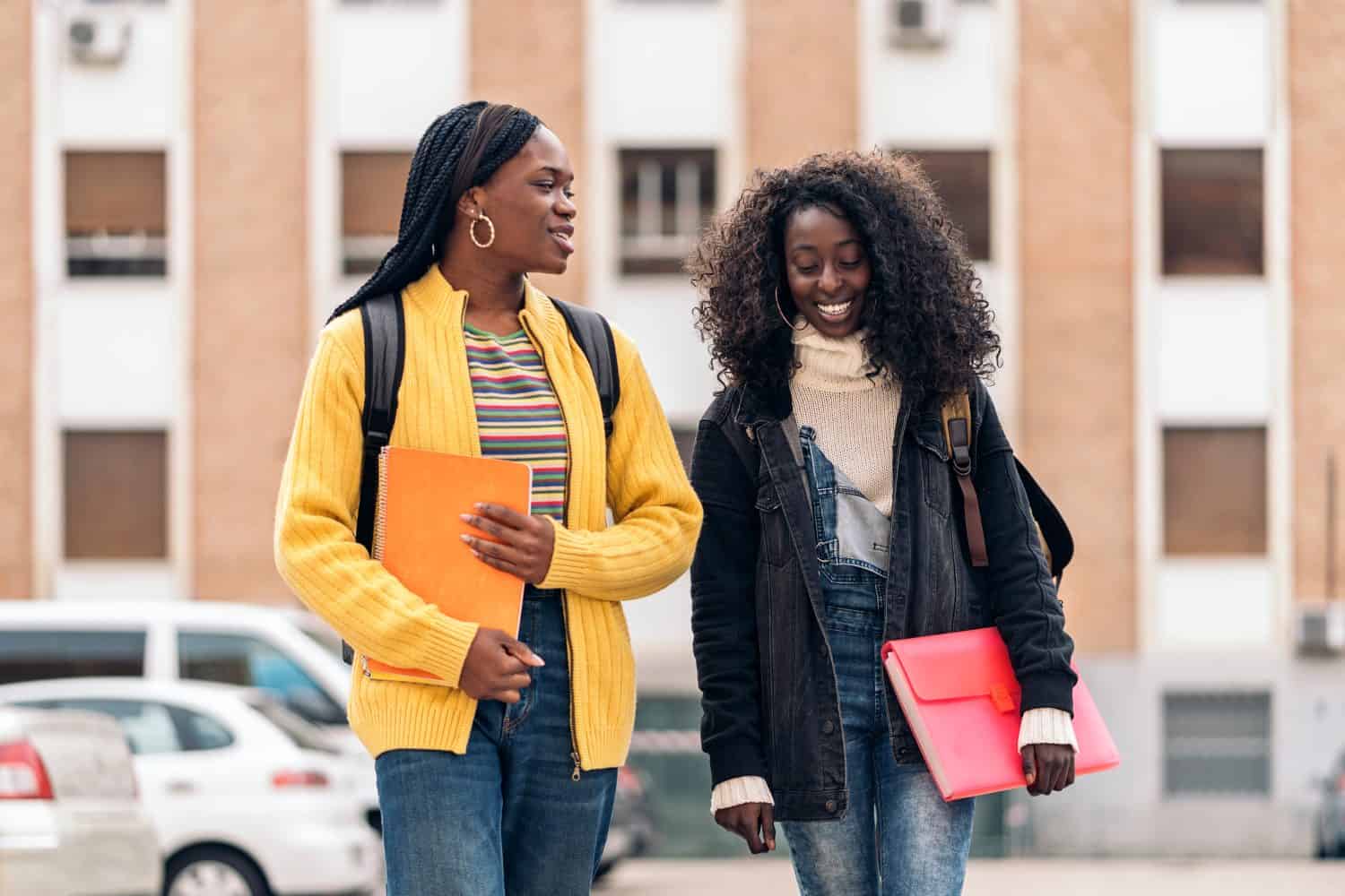 Stock photo of black students talking and laughing in the street.