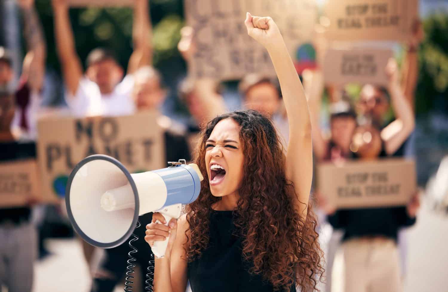 Woman, megaphone and shouting with protest crowd, change or environment justice in city. Bullhorn, loudspeaker and female leader for sustainability, speech or voice for environment politics on road