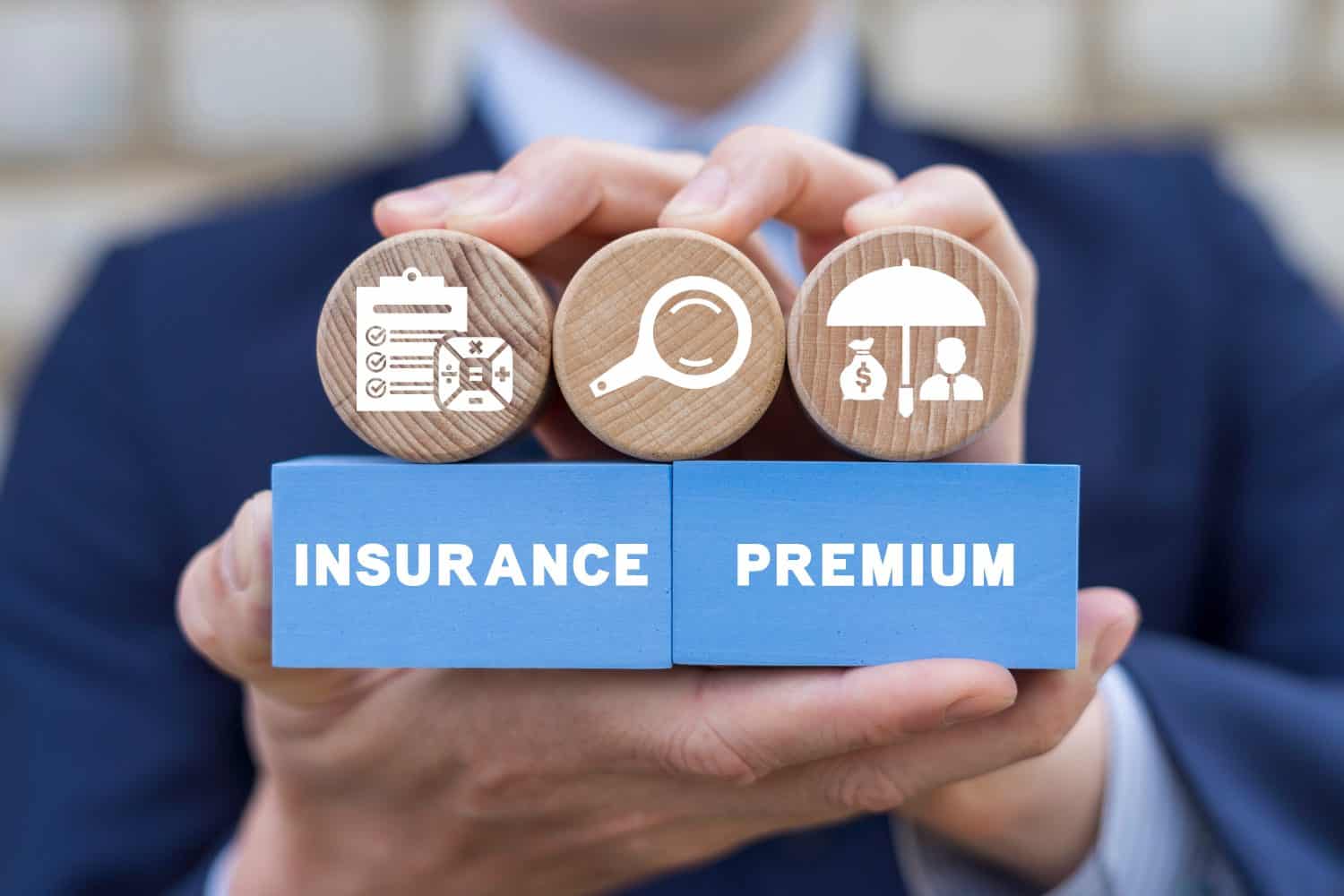 Businessman holding colorful blocks with icons and inscription: INSURANCE PREMIUM. Insurance premium business service concept. Money, life, car, house, health insured.