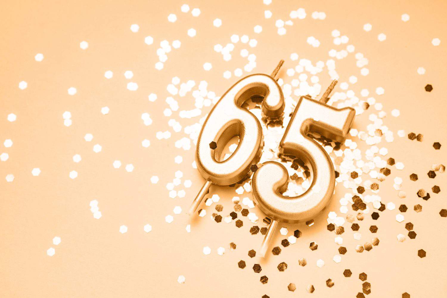 65 years celebration festive background made with golden candles in the form of number Sixty-five lying on sparkles. Universal holiday banner with copy space.