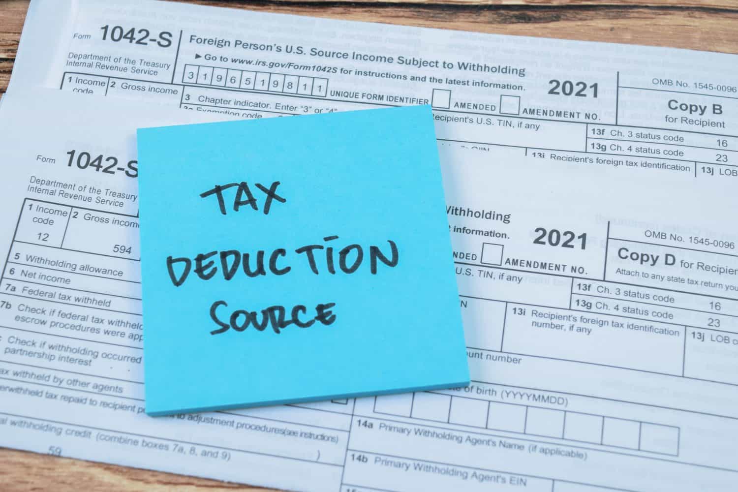 Concept of Tax Deduction Source write on sticky notes isolated on Wooden Table.