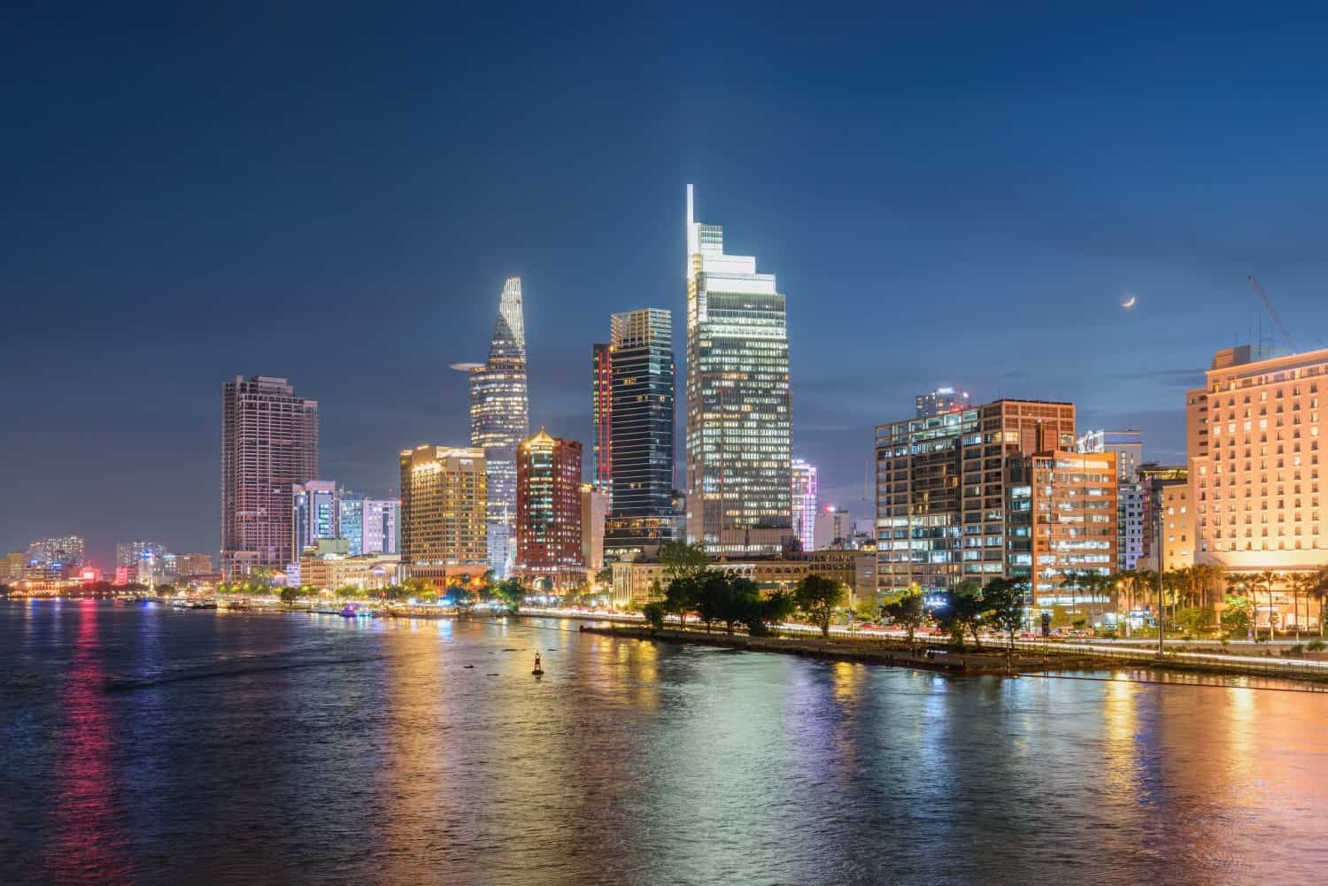 Awesome Ho Chi Minh City skyline. Night view of skyscrapers and other high-rise buildings at downtown of Ho Chi Minh City, Vietnam. Colorful city lights reflected in water of the Saigon River.