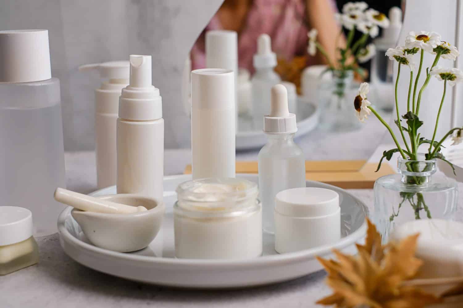 The collection of white skincare products on a tray for beauty and self-care routines.