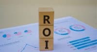 ROI (Return of Investment) symbol. Copy space. Concept word ROI on wooden blocks with diagram chart on the background. Business and financial concept.