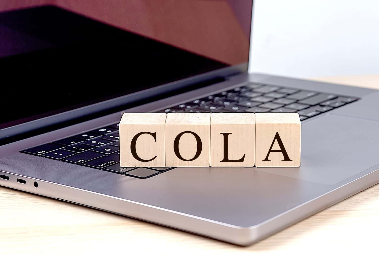 COLA word on wooden block on laptop , business concept.