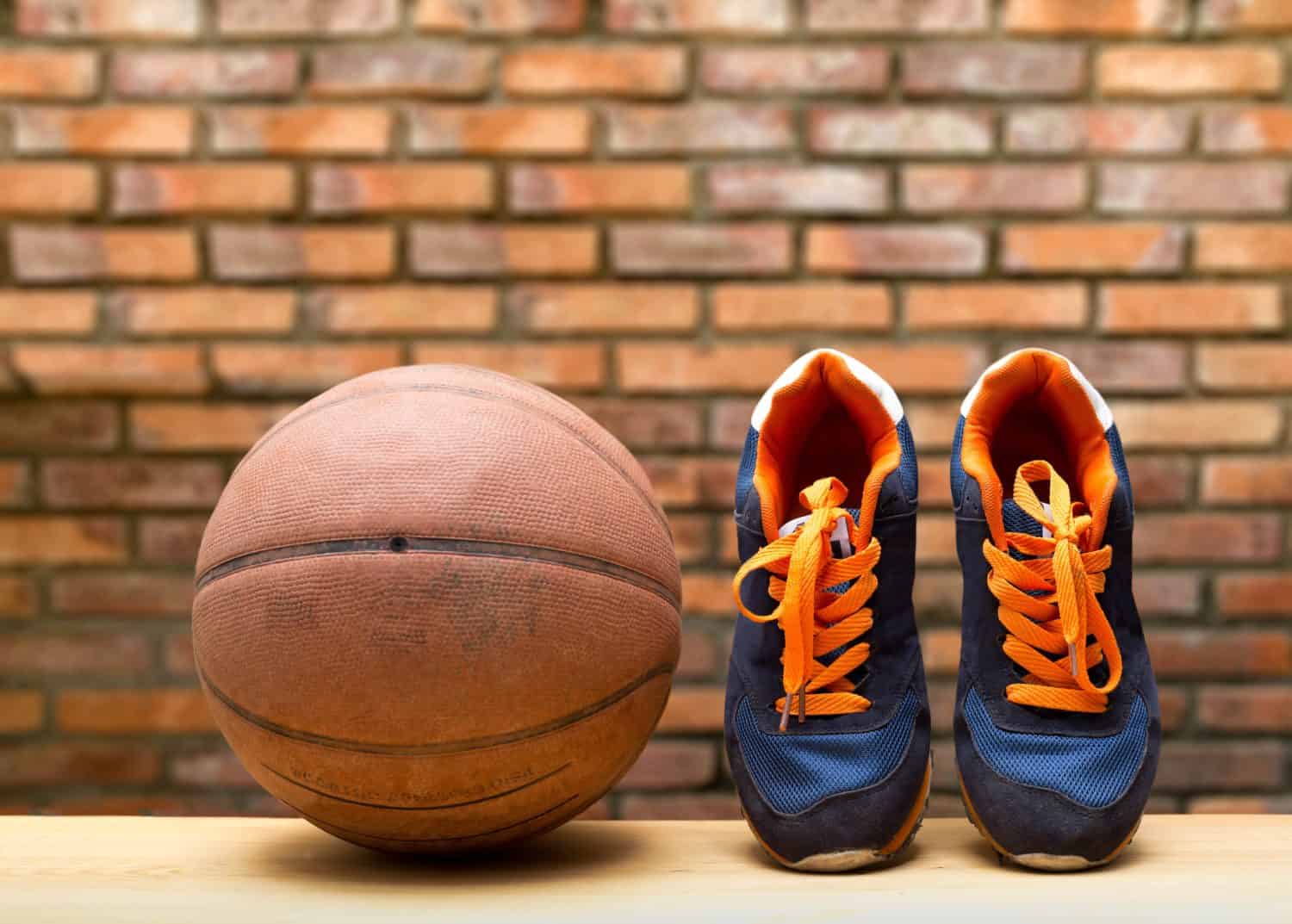 Pair of sport shoes and basketball ball with blur brick wall in background