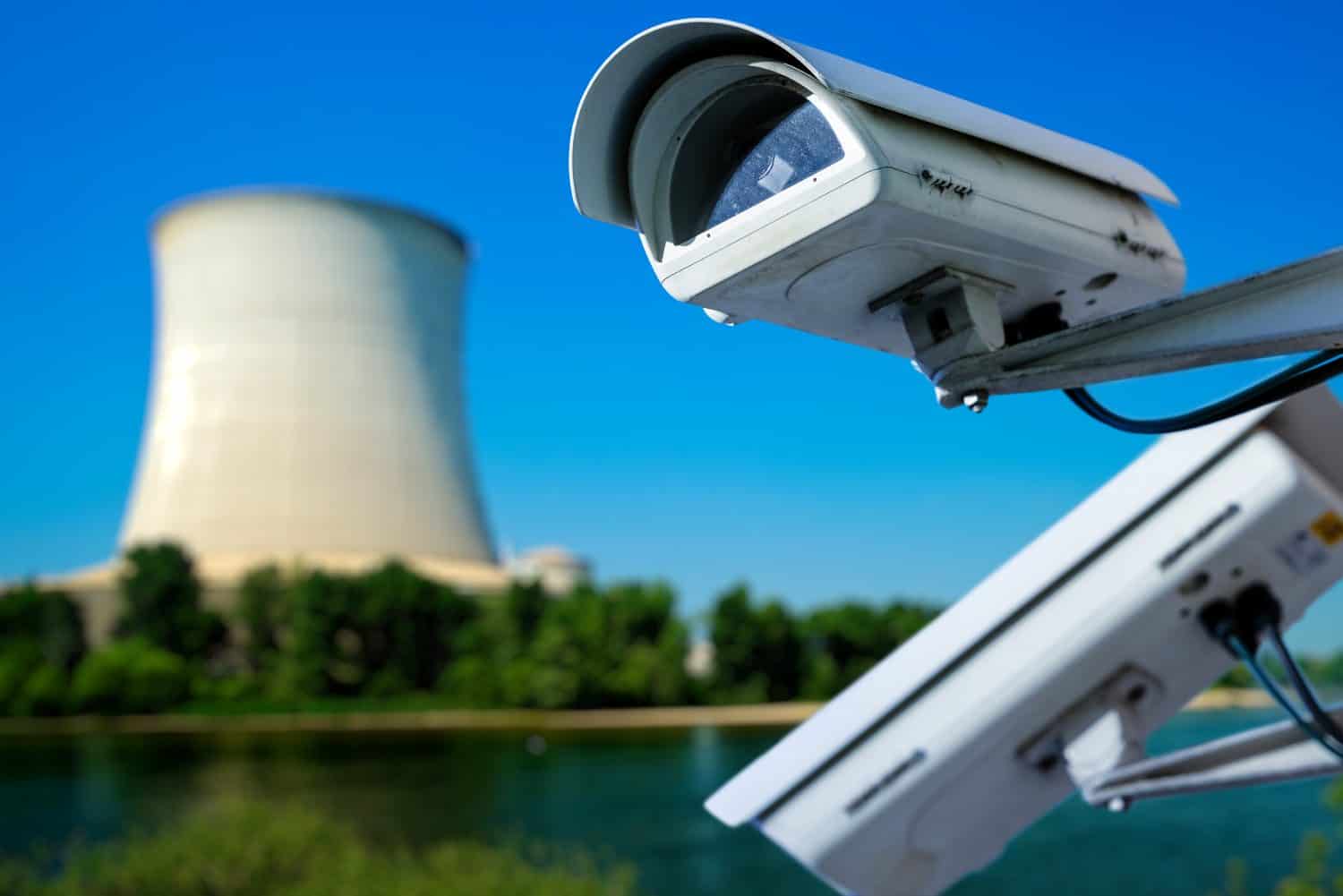 closeup image of CCTV security camera and blurred atomic power plant on background