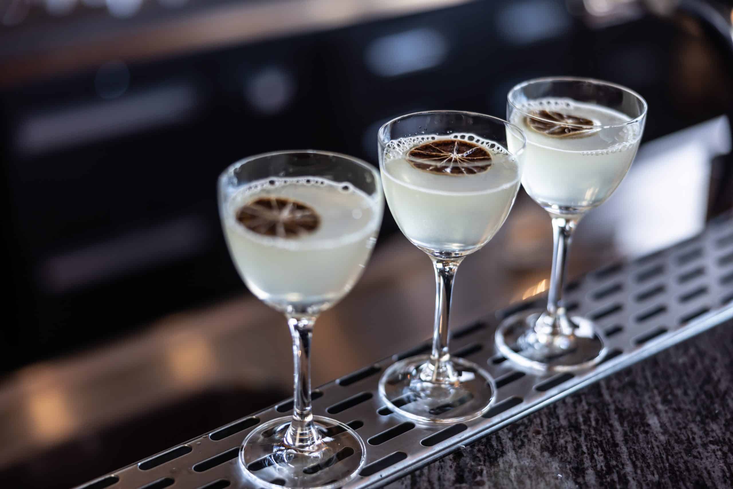 Gimlet or Daiqiri cocktails in three glasses on bar counter.