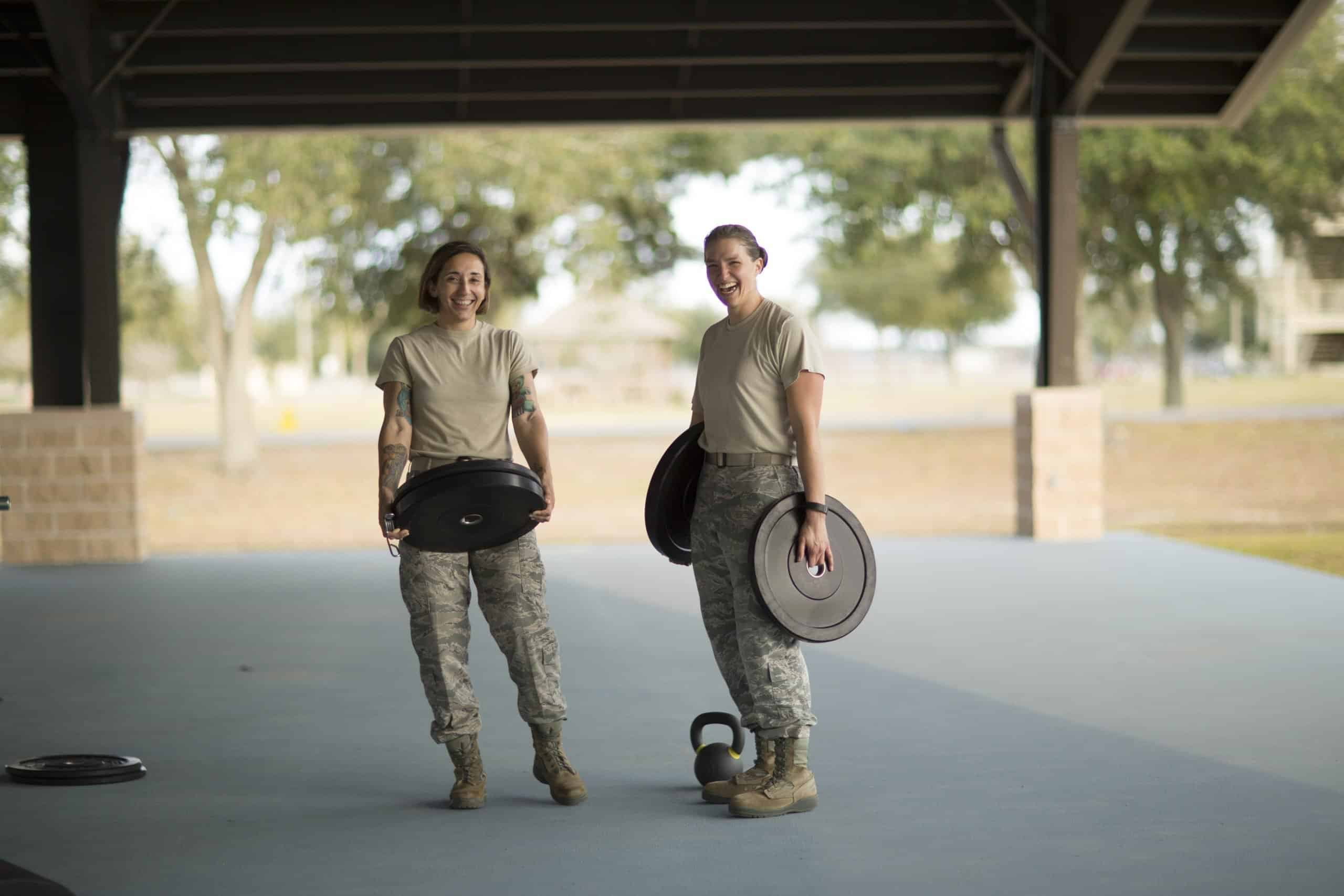 Portrait of two female soldiers barbell training at military air force base