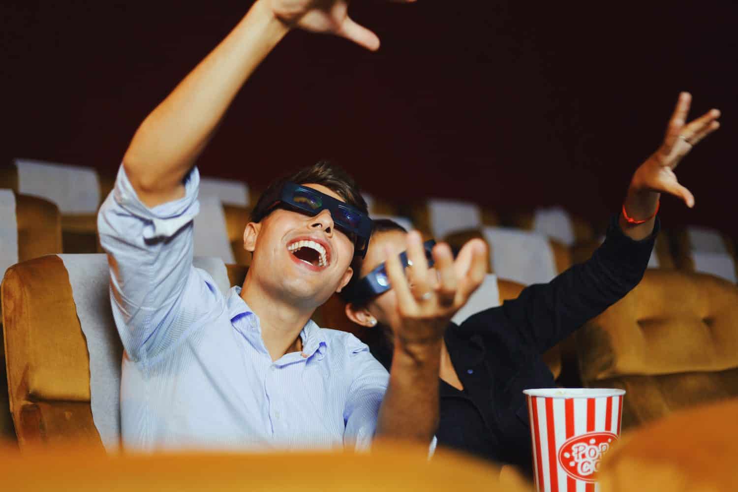 Happy young couple watching 4d movie in cinema.