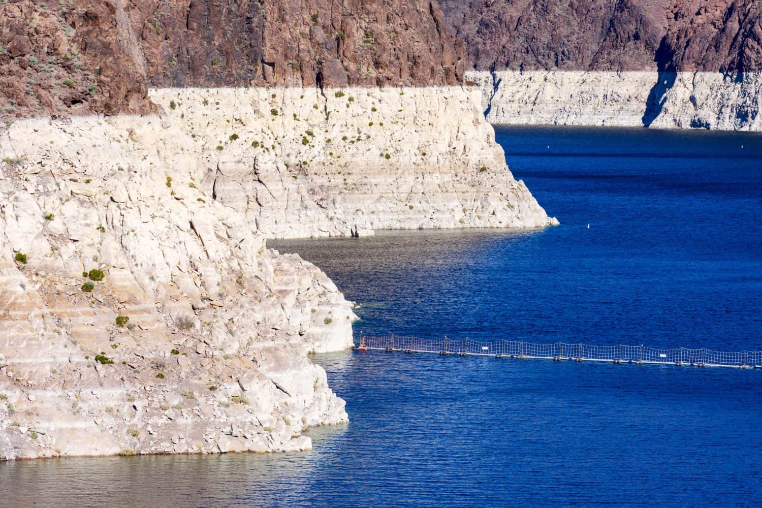 Record low water level of shrinking Lake Mead exposed white surface on rocky banks amid severe drought in American West. The lake is key reservoir along Colorado River