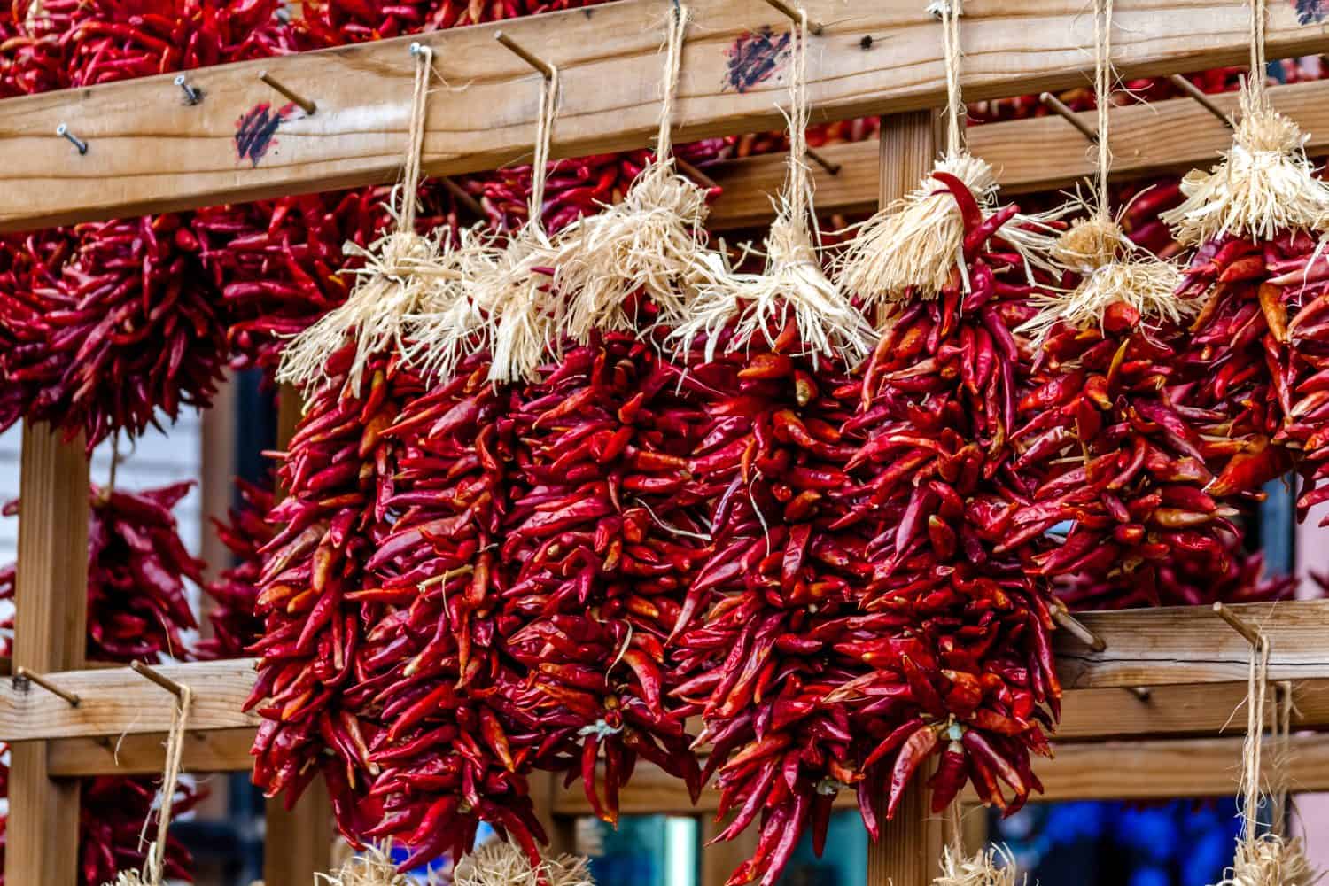 Bunches of dried red chili pods hanging as decorative ristras at local farmers market