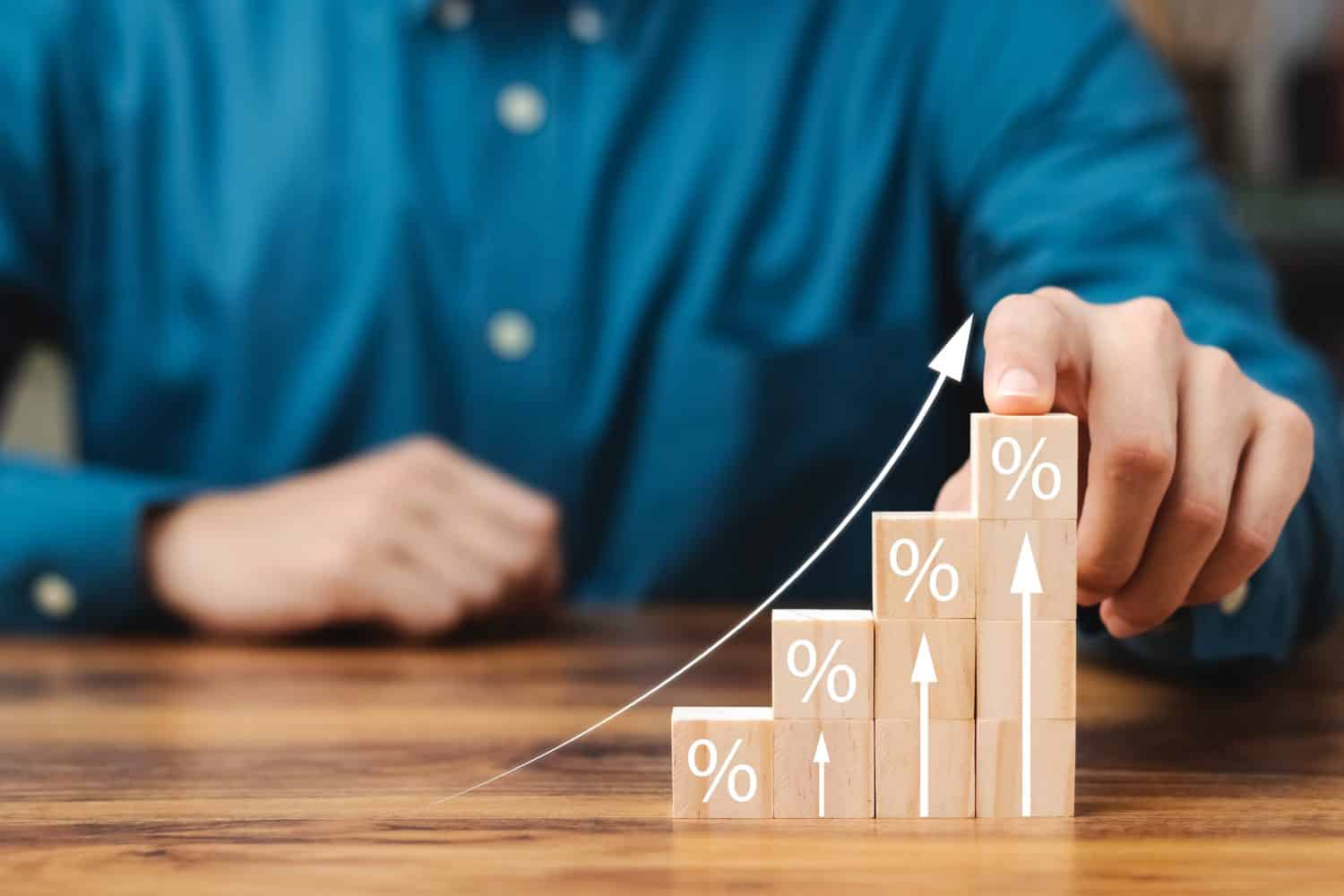 Interest rate and dividend concept, wooden block with percentage symbol and up arrow, return on stocks and mutual funds, long term investment for retirement.