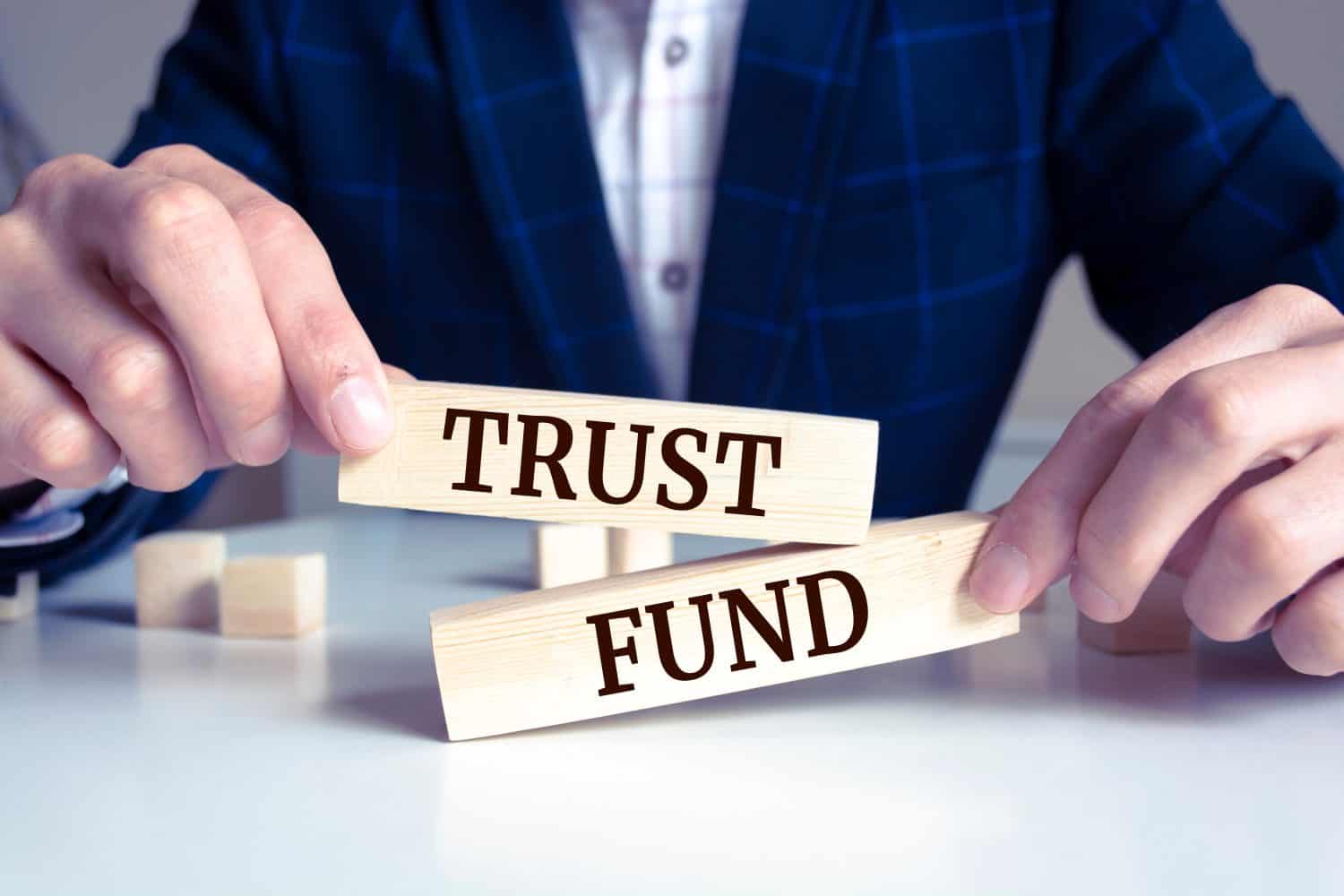 Close up on businessman holding a wooden block with "Trust Fund" message